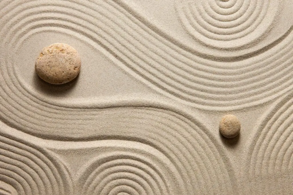 Two stones placed in a zen garden, symbolizing balance, mental health, and holistic lifestyle coaching.