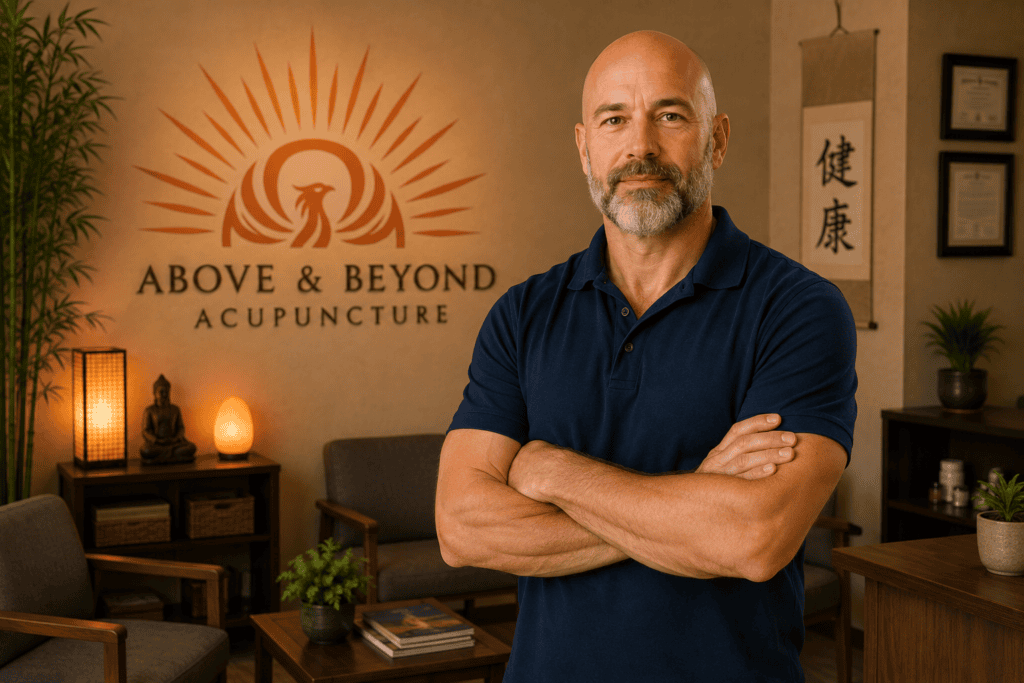 Licensed acupuncturist standing in the welcoming reception area of Above & Beyond Acupuncture with the clinic logo displayed behind him.