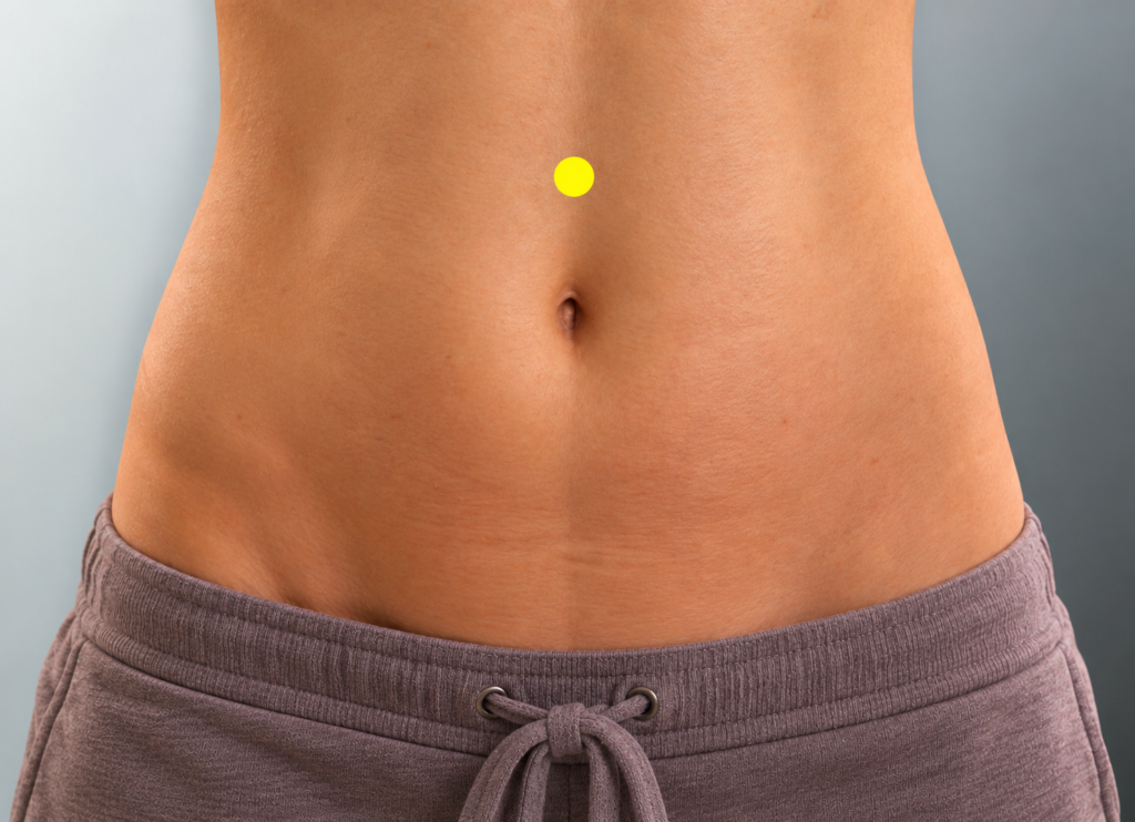 Close-up of a modestly framed abdomen with a yellow dot marker on the midline two finger-widths above the navel, indicating CV10.
