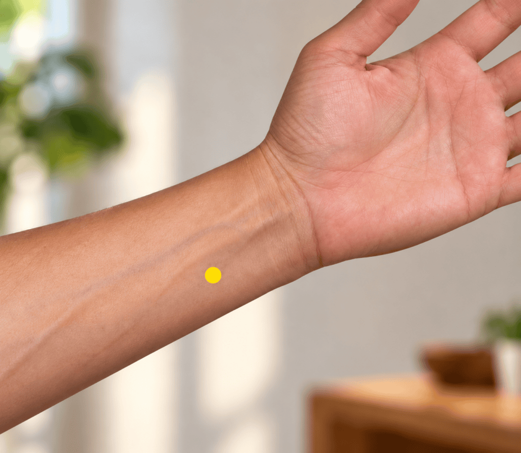 Close-up of an inner forearm with a yellow dot marker a thumb-width above the wrist crease on the pinky side, indicating HT4.