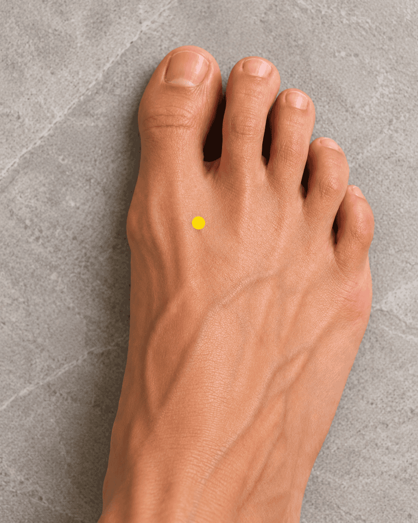 Close-up of the top of a foot with a yellow dot marker in the webbing between the big toe and second toe, indicating LR3.