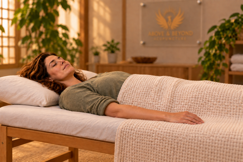 Woman resting peacefully on a treatment table under a blanket, fine needles in her forearm