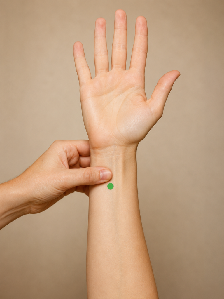 Close-up of the inner forearm, with a green dot marking PC5 four finger-widths above the wrist crease.
