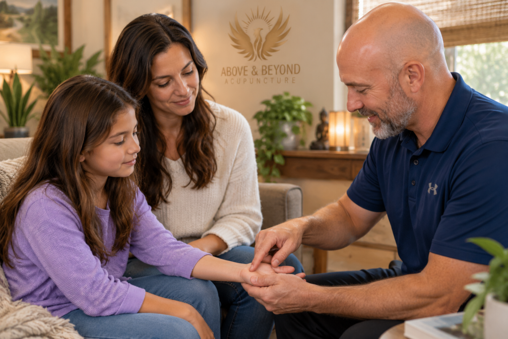 Parent and child sitting with an acupuncturist who is showing them a point on the child’s hand.