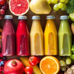 A colorful assortment of juices surrounded by fruits, related to the Nutrition blog post, 'Three Things You Should Never Juice'