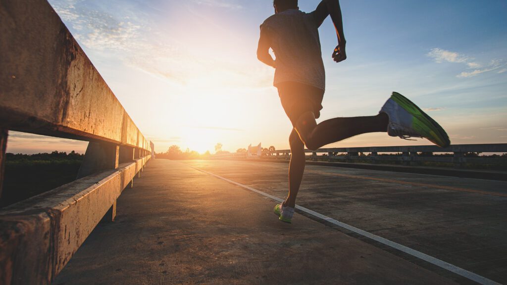 A man running on a road toward the sunrise, symbolizing sports health, perseverance, new beginnings, and a journey toward better health and wellness. Related to the Treatment blog post, 'Top Athletes Who Use Acupuncture'.