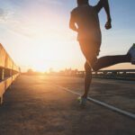 A man running on a road toward the sunrise, symbolizing sports health, perseverance, new beginnings, and a journey toward better health and wellness. Related to the Treatment blog post, 'Top Athletes Who Use Acupuncture'.