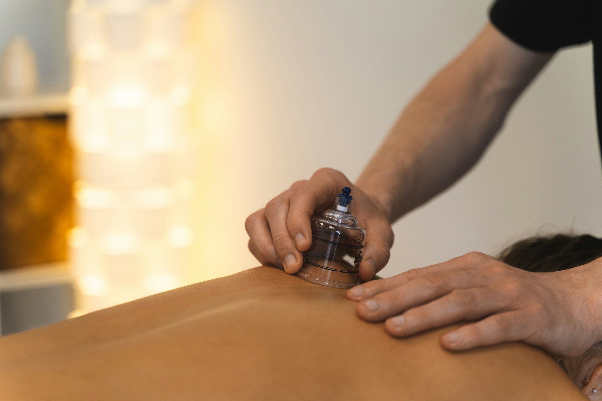 Practitioner applying a running suction cup to a patient's back during a myofascial decompression treatment in Scottsdale.