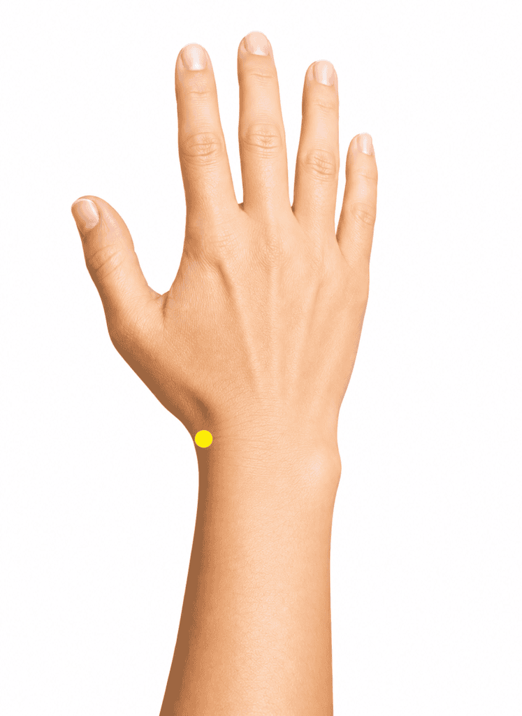 Close-up of a wrist with a yellow dot marker in the hollow on the thumb side, indicating LI5.