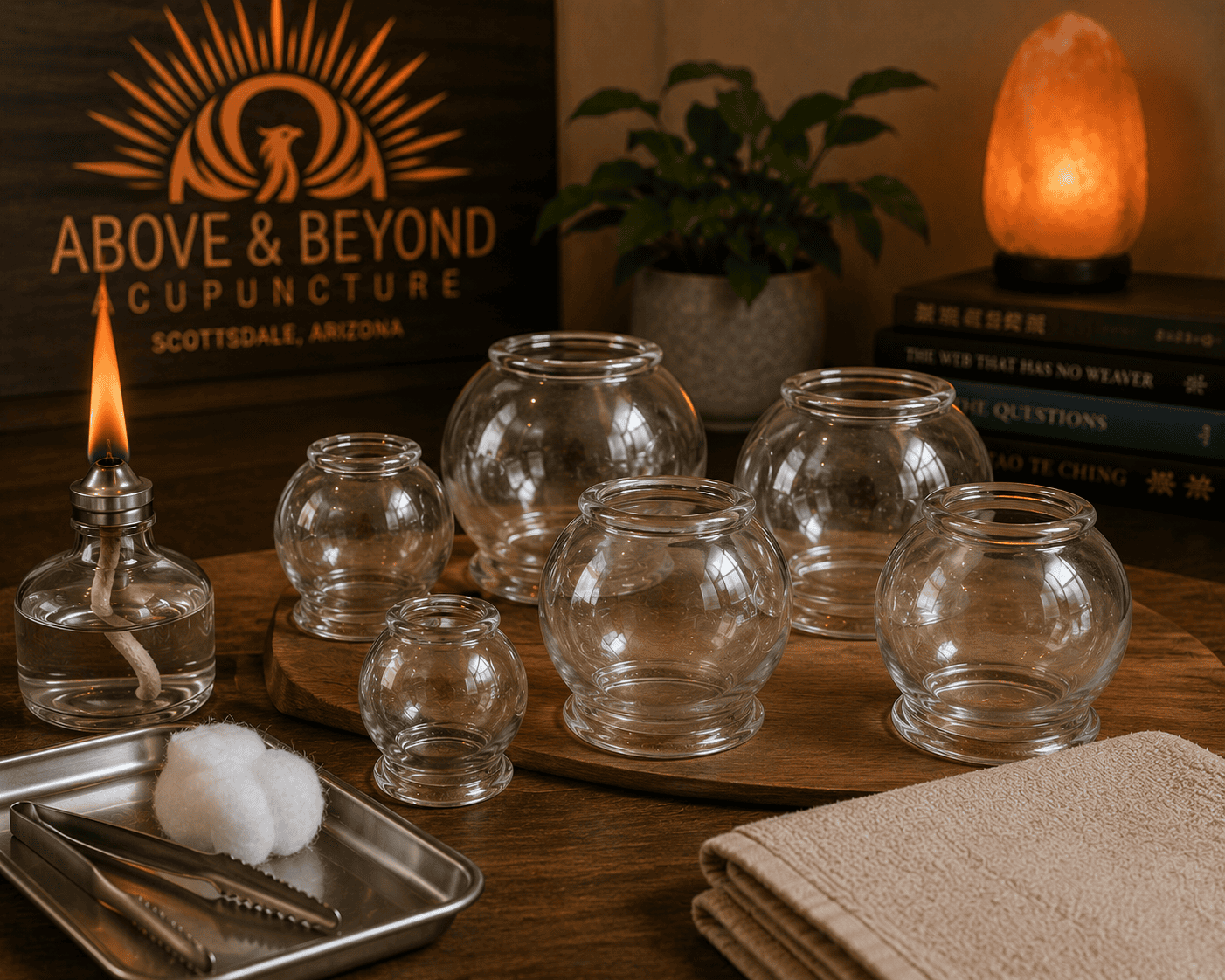 Traditional glass fire cupping cups arranged with an alcohol lamp, cotton, and metal tongs in a professional acupuncture clinic.